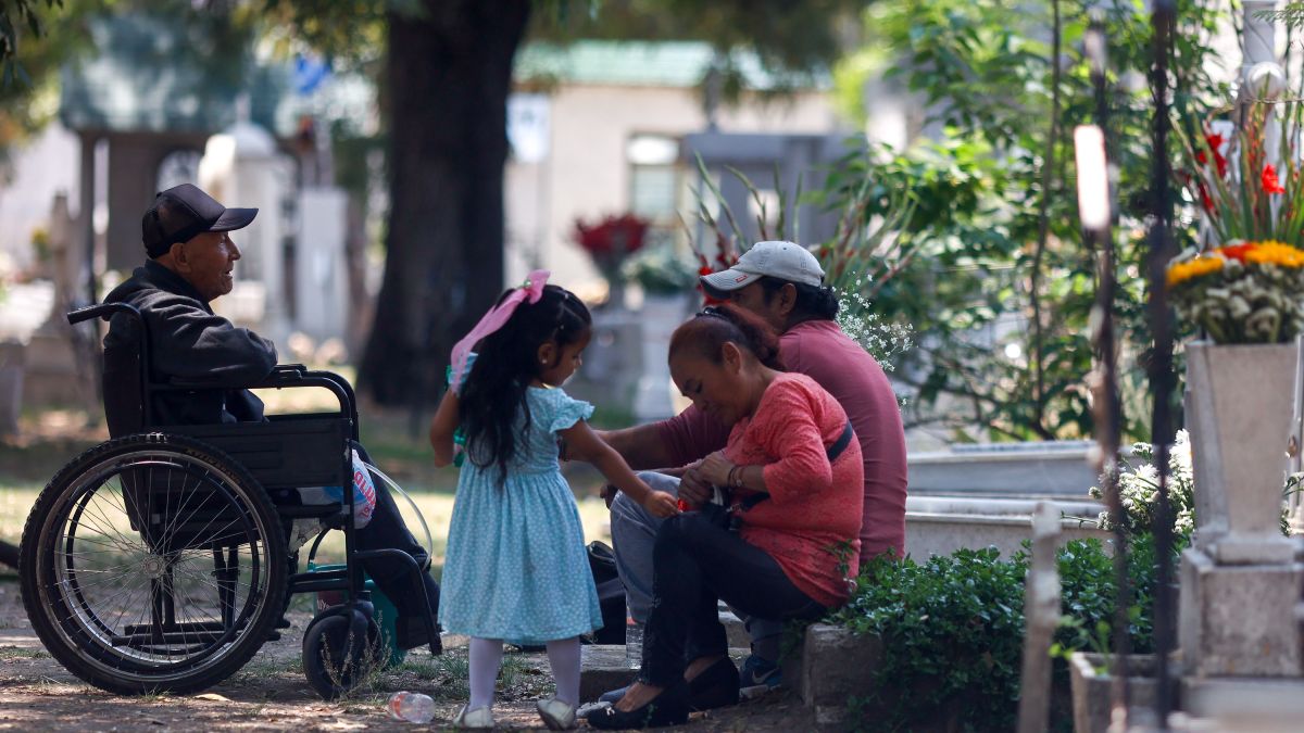 Familias sentadas junto a las tumbas de su familia