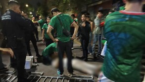 Grupo de personas con la playera de la Selección Mexicana y elementos de la Policía de Guadalajara rodeando a un hombre herido tendido en la calle