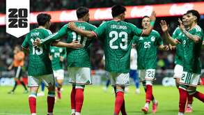 Jugadores de la selección mexicana abrazados en la cancha vistos por la espalda