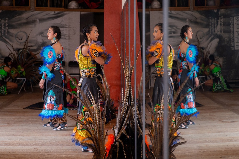 Mujeres bailando en un salón frente a un espejo.