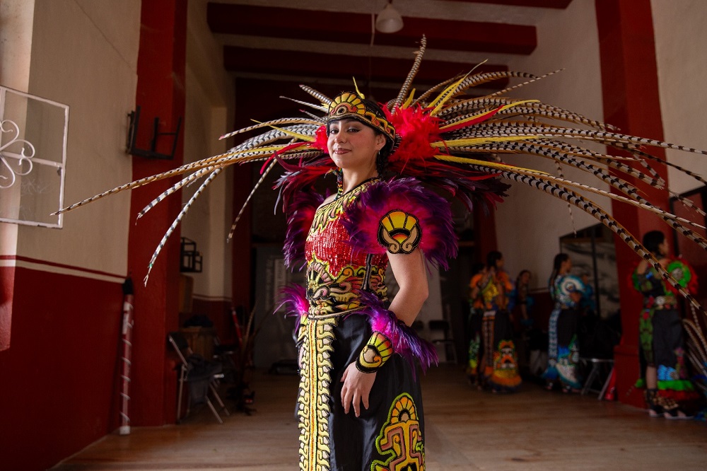 Mujer con traje azteca sonriendo para una fotografía.