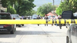 Se observa una cintilla amarilla de precaución y una camioneta blanca de fondo.