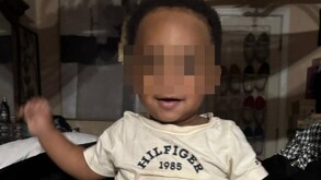 Bebé afroamericano de un año identificado como Kohen Wiley con los ojos censurados por un cuadro pixeleado y con una playera de Tommy Hilfiger