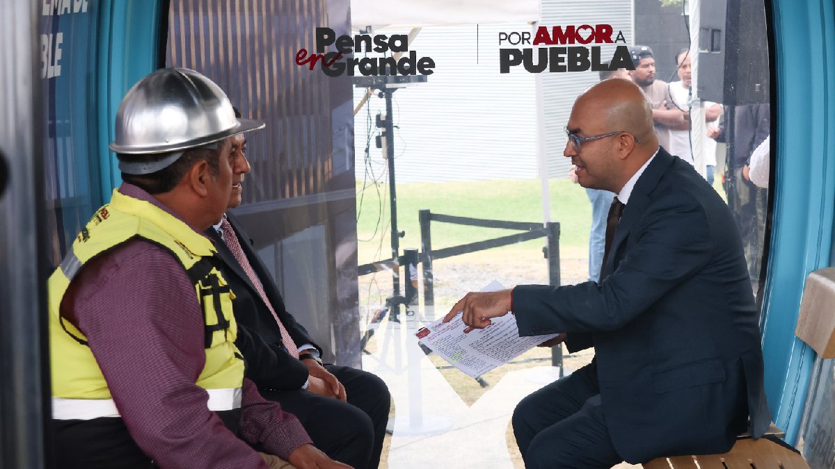 Hombres sentados al interior de una cabina de cablebús.