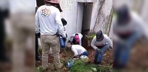 Hombres y mujeres integrantes de un colectivo de búsqueda excavando el terreno dentro de una casa abandonada donde hallaron cuerpos humanos
