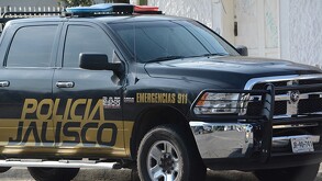 Vista del costado de una patrulla de la Policía del Estado de Jalisco estacionada al exterior de una viviendas con fachada color blanco
