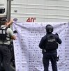 Policías soteniendo una manta junto a un tráiler recuperado.