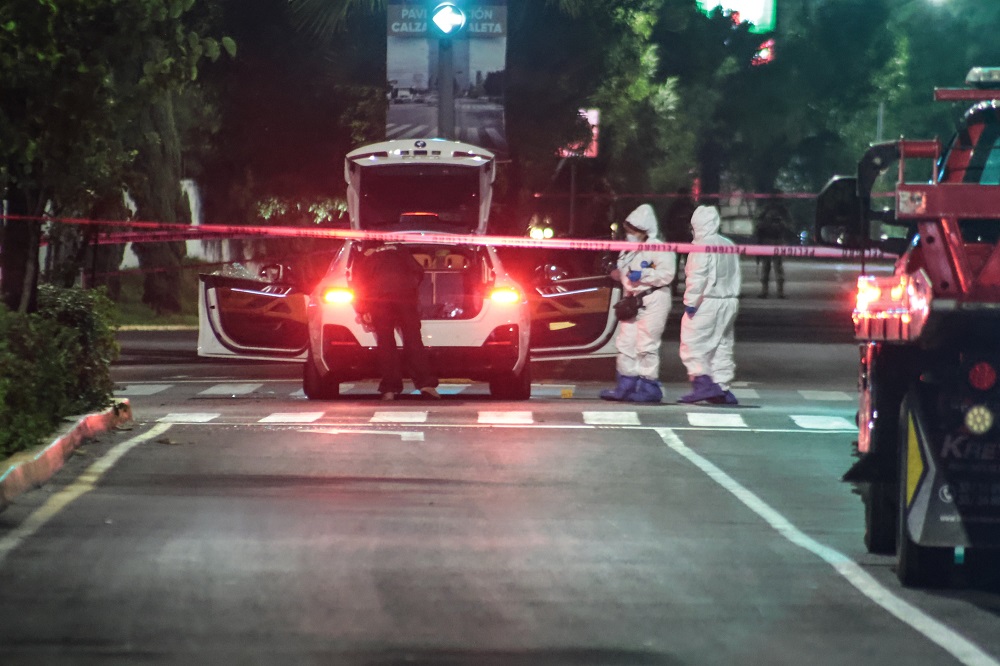 Peritos indagan en un vehículo donde asesinaron a una persona en calles de Puebla.