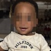 Bebé afroamericano de un año identificado como Kohen Wiley con los ojos censurados por un cuadro pixeleado y con una playera de Tommy Hilfiger