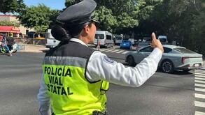 Mujer agente de la Policía Vial de Jalisco dando señales de siga para controlar el tráfico de autos en calles de Guadalajara