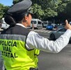 Mujer agente de la Policía Vial de Jalisco dando señales de siga para controlar el tráfico de autos en calles de Guadalajara
