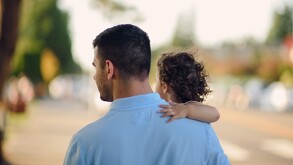 Un hombre cargando a una niña vistos de espaldas