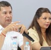 Hombre apuntando al frente con el dedo, sentado junto a una mujer.