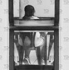 Vista de espaldas a una mujer sentada en una mesa de madera.