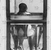 Vista de espaldas a una mujer sentada en una mesa de madera.