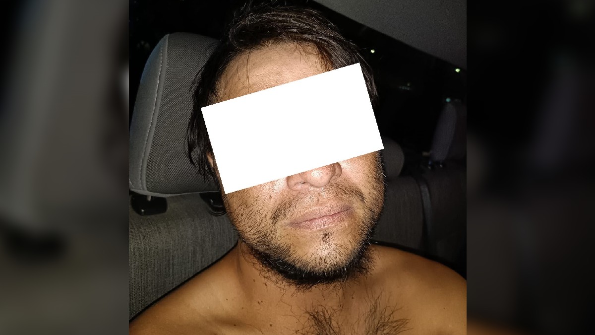 Hombre sin playera y con los ojos censurados por un rectángulo blanco dentro de una patrulla de la Policía de Guadalajara