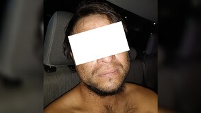 Hombre sin playera y con los ojos censurados por un rectángulo blanco dentro de una patrulla de la Policía de Guadalajara