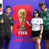 Dos hombres y una mujer delante de un cartel promocional del Fan Fest del Mundial en Guadalajara