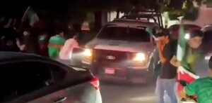 Patrulla de la Policía Municipal de Apatzingán siendo rodeada y empujada por fanáticos con playeras de la Selección Mexicana