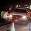 Patrulla de la Policía Municipal de Apatzingán siendo rodeada y empujada por fanáticos con playeras de la Selección Mexicana