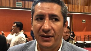 Hombre vestido de traje es entrevistado por la prensa.