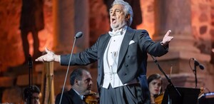 El tenor español Plácido Domingo cantando durante un concierto con músicos alrededor de él en un escenario