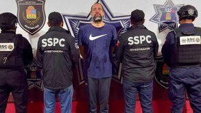 un hombre detenido y varios policías custodiándolo