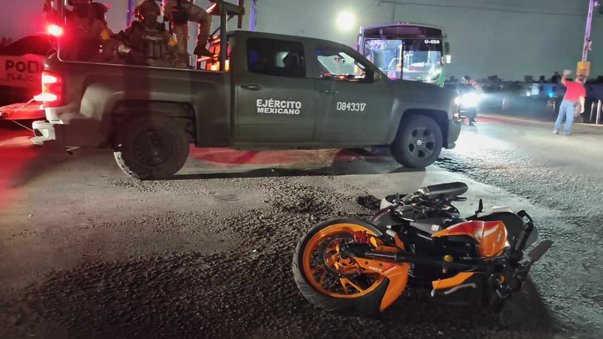 Camioneta de la Guardia Nacional con militares a bordo al lado de una motocicleta naranja tumbada sobre el asfalto