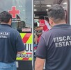 Agentes de la Fiscalía de Jalisco vistos de espaldas con una ambulancia de la Cruz Roja con paramédicos dando atención a una mujer de la tercera edad