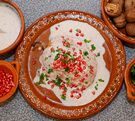 Chile en nogada servido en un plato tradicional de Puebla junto con todos sus aditamentos.