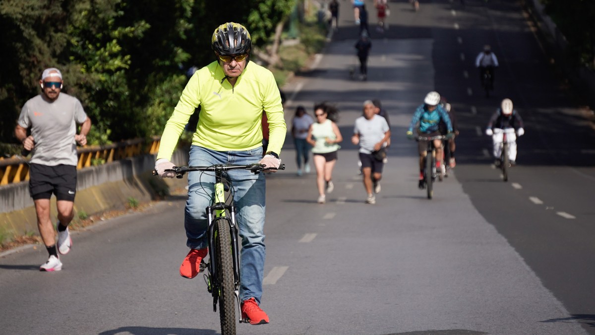 un hombre andando en bici y personas corriendo detrás
