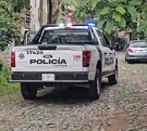 Vista de la parte de atrás de una patrulla de la Policía de Tlaquepaque estacionada en un camino empedrado con un auto enfrente