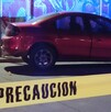 Automóvil color rojo estacionado en la calle al lado de una pared con un grafitti y una cinta policiaca acordonando el sitio