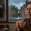 Persona mira con curiosidad una cuchara detrás una ventana empañada por la lluvia