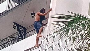Hombre con la playera en la cabeza brincando por el balcón de un hotel en Puerto Vallarta