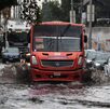 Camión y autos avanzando en una calle inundada por la lluvia en Puebla.