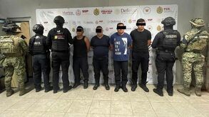 cuatro hombres detenidos custodiados por policías