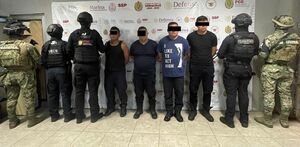 cuatro hombres detenidos custodiados por policías