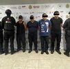 cuatro hombres detenidos custodiados por policías