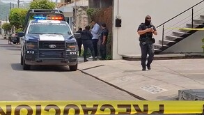 Patrulla y oficiales de la Policía de Colima en un área acordonada por una cinta policiaca tras un ataque a balazos en un autolavado