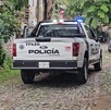 Vista de la parte de atrás de una patrulla de la Policía de Tlaquepaque estacionada en un camino empedrado con un auto enfrente