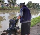 dos mujeres retiran basura de la orilla de una laguna