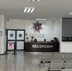 Se observa a dos personas sentadas y hay un escritorio que dice Recepción.