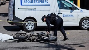 Mujer oficial de la Policía de Tlajomulco acercándose a una motocicleta tumbada sobre el asfalto tras un accidente automovilístico