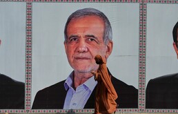 Una mujer camina junto a un cartel de bienvenida con la imagen del presidente de Irán, Masoud Pezeshkian, junto a una calle en Islamabad, Pakistán