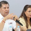 Hombre apuntando al frente con el dedo, sentado junto a una mujer.