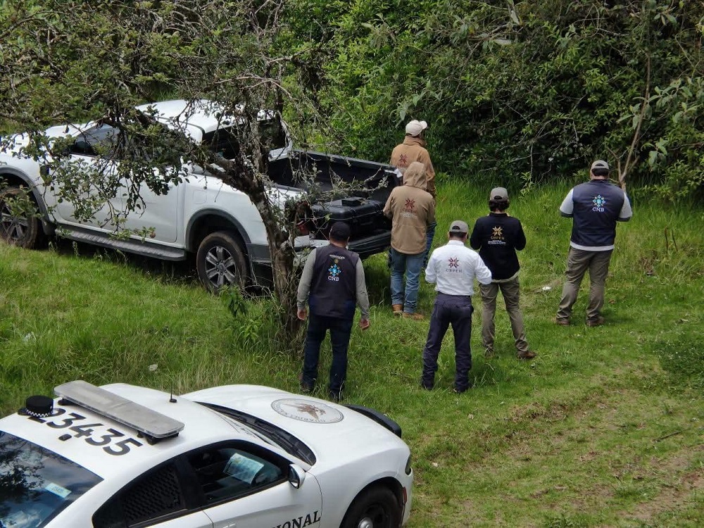 Personal de búsqueda junto a una camioneta abandonada.