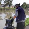 dos mujeres retiran basura de la orilla de una laguna