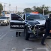 Patrulla de la Policía de Guadalajara atravesada en la calle con las puertas abiertas e impactada de la parte del frente y un policía caminando frente a ella