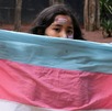 una menor de edad sostiene una bandera de la comunidad transgénero